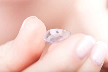 Image of hand holding a contact lens.