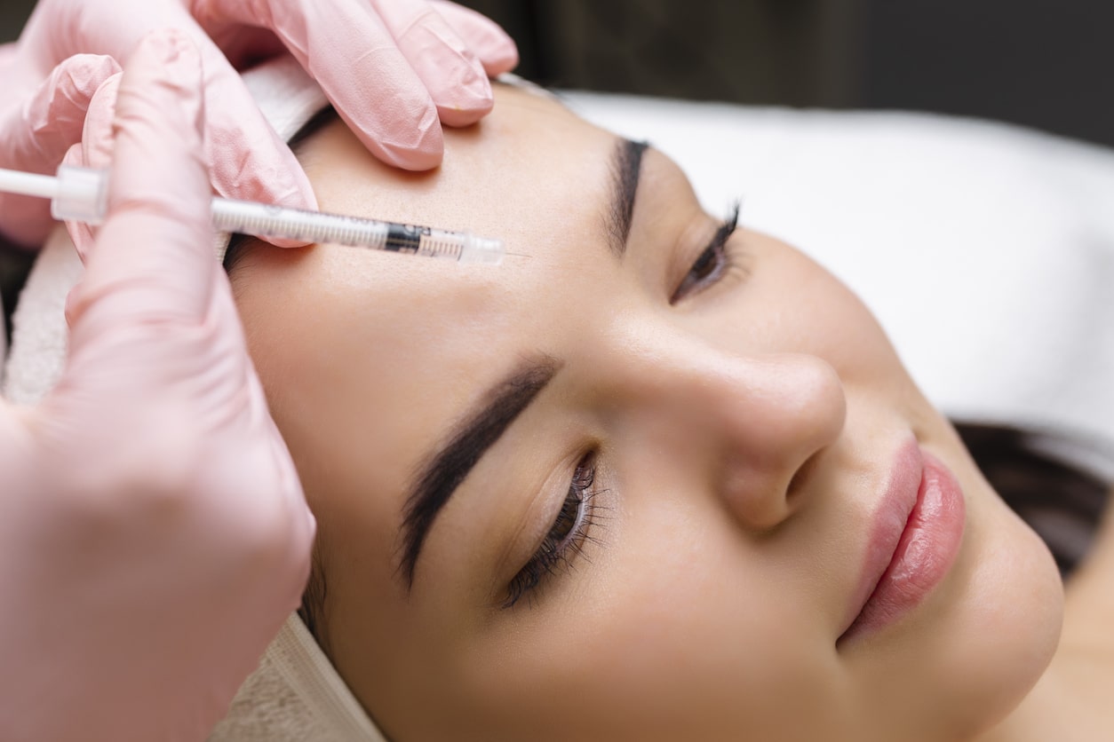 A woman relaxes as a Provo, Utah, Botox aesthetician selects the placement point of her injection.