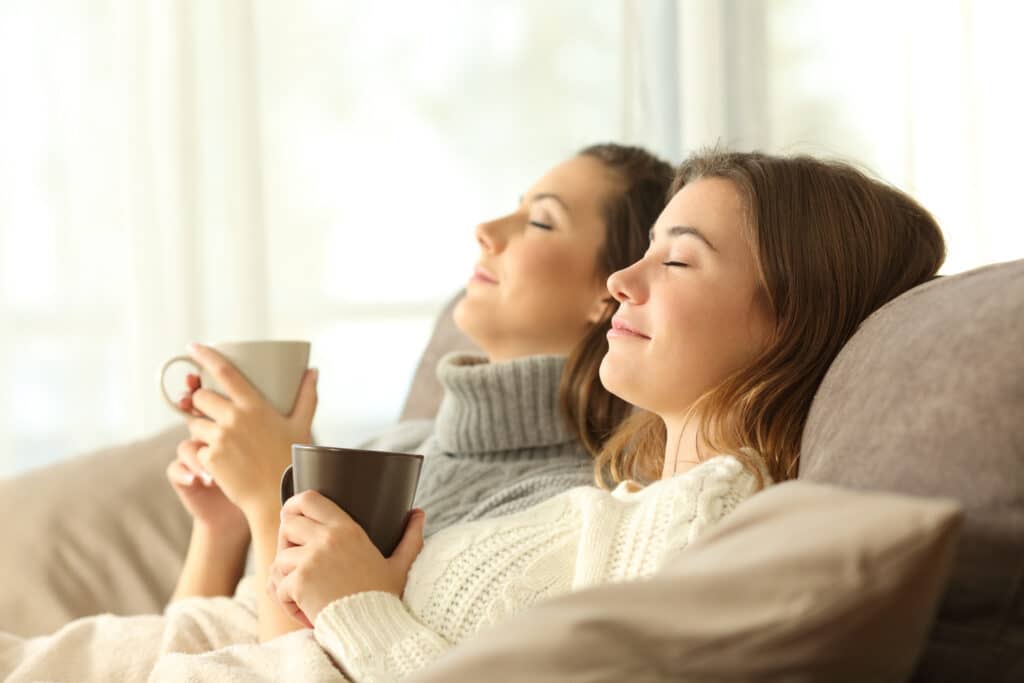Two women enjoy the New Year by relaxing at home with warm drinks after getting the best facials.