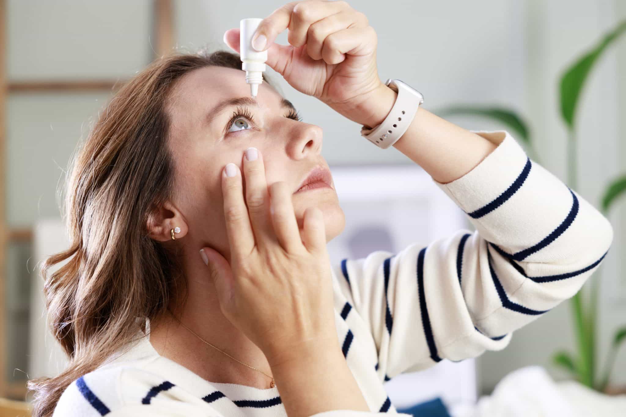 A woman applies traditional eye drops and considers seeking more advanced solutions for chronic dry eye syndrome.