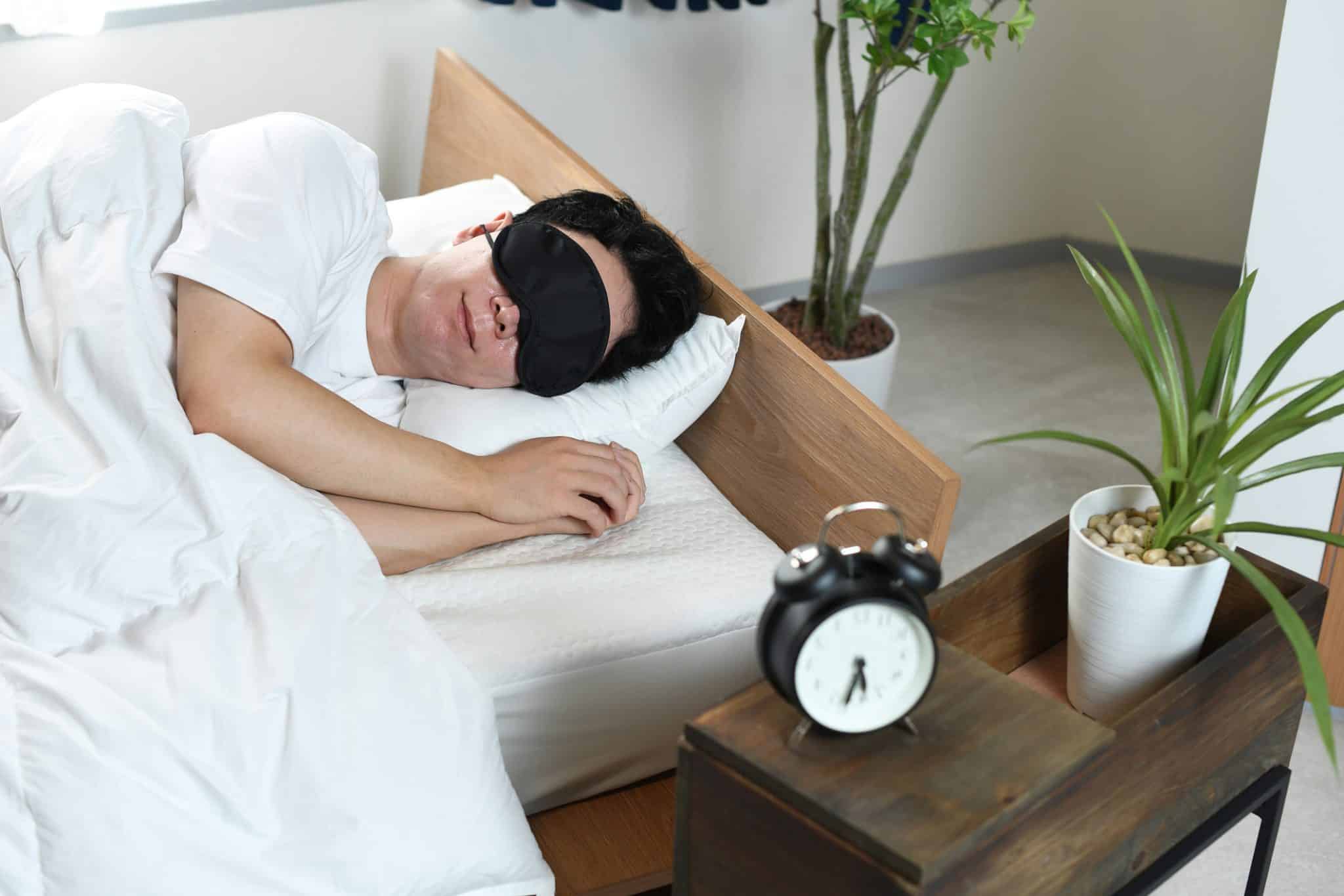 A man sleeping with an eye mask in an effort to alleviate nighttime dry eye symptoms and promote eye health.