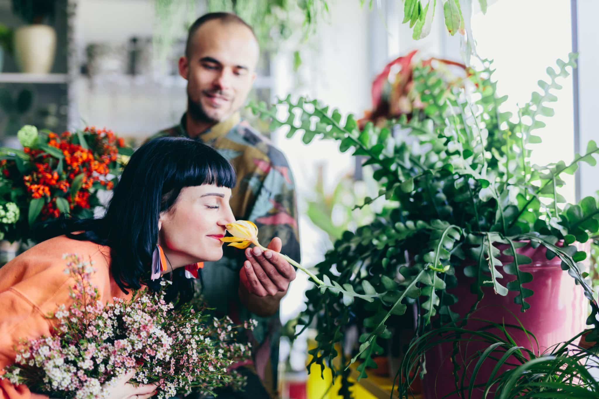 A couple smells flowers in a florist’s shop, representing moments that are more enjoyable when allergies are kept in check.