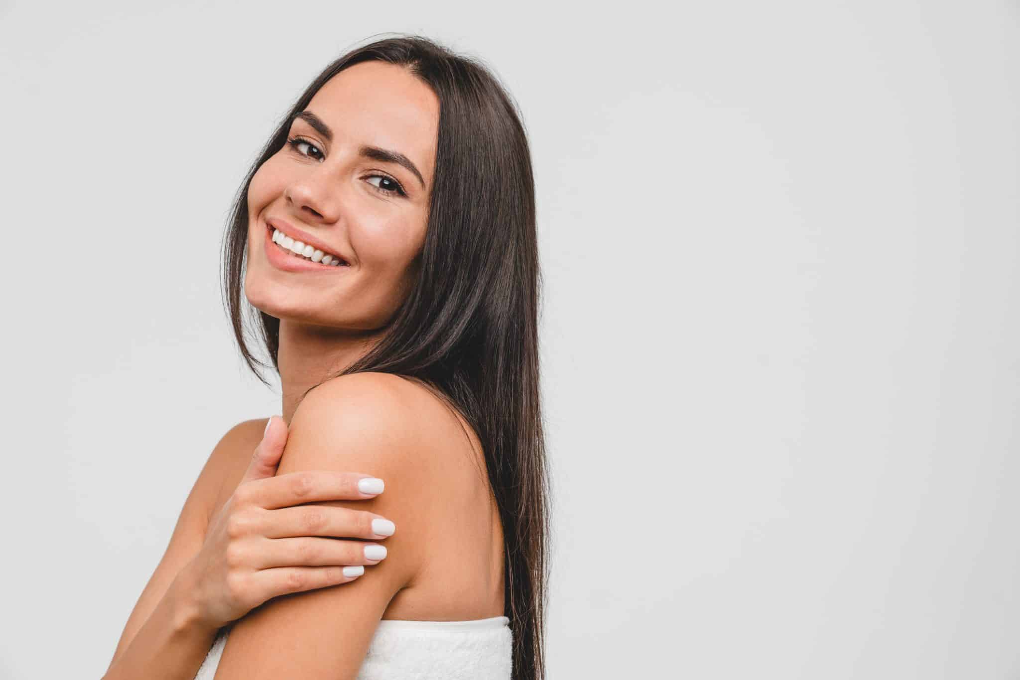 Smiling woman in a spa towel with glowing, rejuvenated skin after microneedling treatment in Provo, UT.