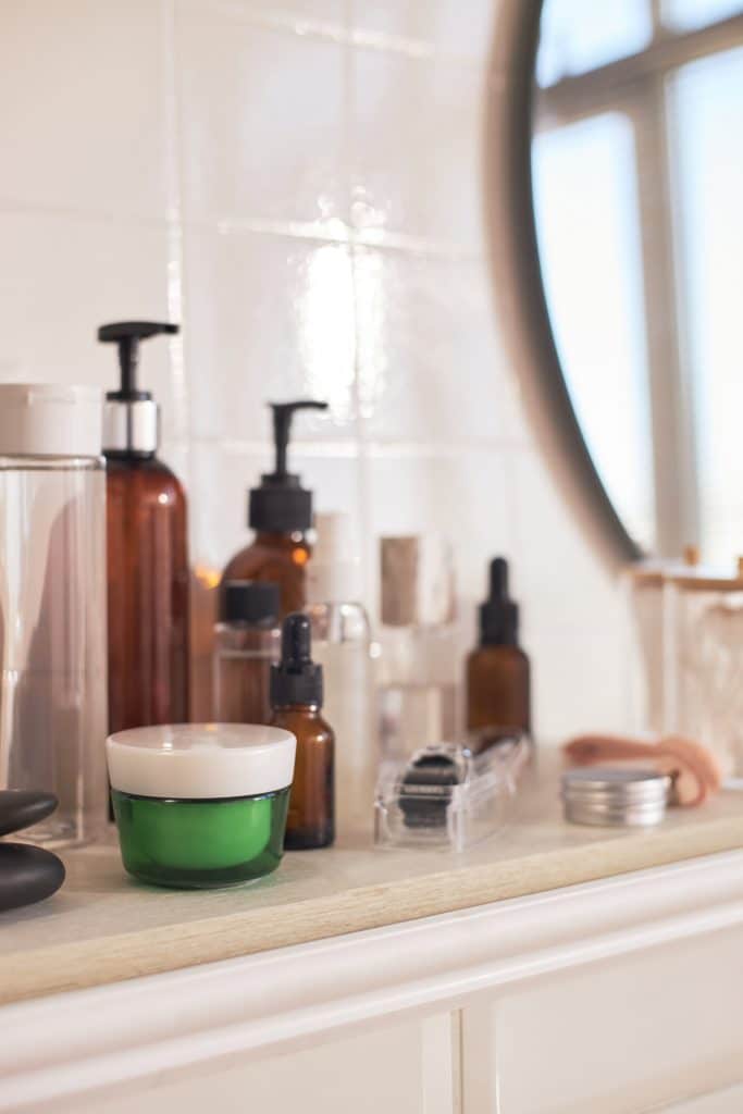 Assorted skincare products on a bathroom counter representing ineffective at-home treatments for rosacea and sensitive skin.
